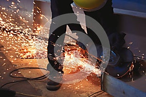 Professional worker cuts metal by angle grinder machine. Fountain of sparks. Fire safety at construction site