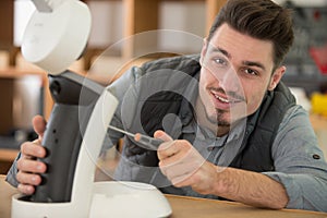 professional worker in eyeglasses and protective workwear fixing coffee machine