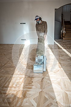 Professional worker grinding a parquet floor with special machine