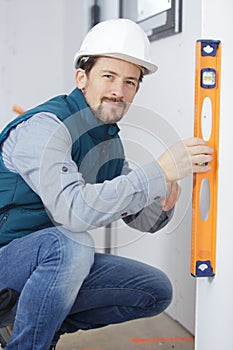 professional worker in helmet measuring wall with level