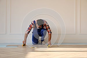 Professional worker installing new parquet flooring indoors