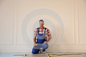 Professional worker installing new parquet flooring indoors