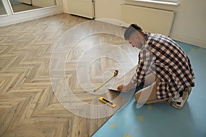 Professional worker installing new parquet flooring indoors