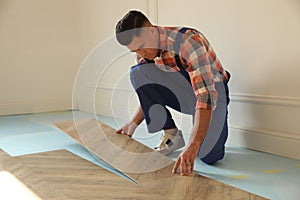 Professional worker installing new parquet flooring indoors