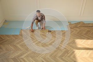 Professional worker installing new parquet flooring indoors, above view