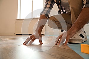 Professional worker installing new parquet flooring indoors, closeup