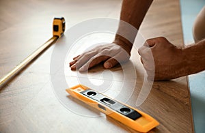 Professional worker installing new parquet flooring indoors, closeup