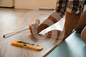 Professional worker installing new parquet flooring indoors, closeup