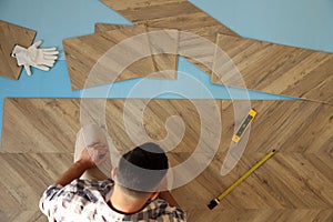 Professional worker installing new parquet flooring indoors, top view