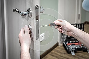 Professional worker installing the part of lock in wooden door by the screwdriver