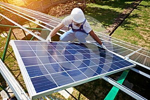 Professional worker installing solar panels on the green metal construction