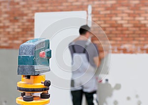 Professional worker lays bricks on the wall using laser level photo