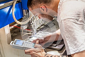 Worker technician engineer programming soft PVC dispensing machine in factory