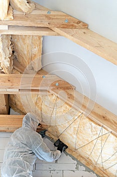 Professional worker in overalls working with rockwool insulation material