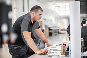 Professional worker printmaker technician operator works in modern printing plant