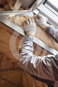 Professional worker putting mineral rockwool insulation in wall photo