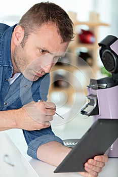 professional worker using tablet for fixing coffee machine