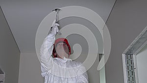 Professional worker in work wear make drywall ceiling holes for light install