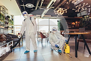 Professional workers in hazmat suits disinfecting indoor of cafe or restaurant, pandemic health risk, coronavirus