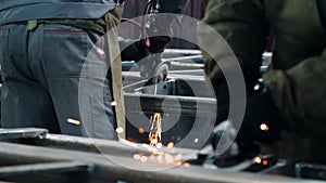 Professional workers polishing metal surfaces with angle grinders in workshop