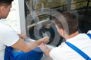 Professional workers tinting window with foil