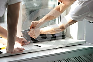 Professional workers tinting window with foil, closeup