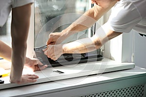 Professional workers tinting window with foil, closeup photo