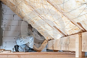 Professional workman installing thermal insulation layer under the roof