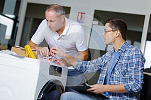 Professional workmen fixing washing machine