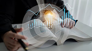 Business analysis with light bulb concept, charts, and graphs over open book for creativity, learning, innovation, and