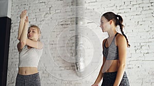 Professional yoga instructor is teaching new student to do arm twists while having individual practice in wellness