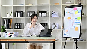 Professional young Asian female financial analyst working in her office