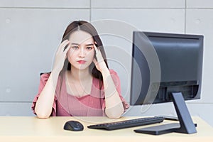 Professional young  Asian professional business woman who wears pink dress is working tired and feeling headache while she works.