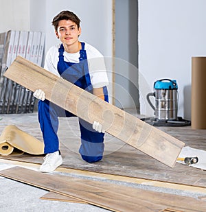 Professional young builder laying laminate flooring in repairable room