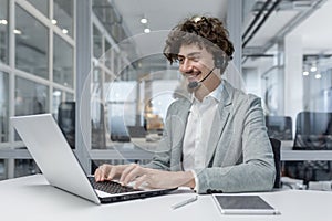 Professional young businessman with headset engaged in online communication in office