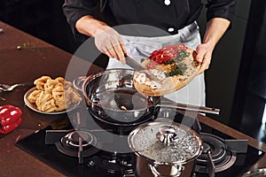 Professional young chef cook in uniform standing and preparing for the work on kitchen