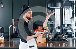 Professional young chef cook in uniform standing and preparing for the work on kitchen