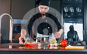 Professional young chef cook in uniform standing and preparing for the work on kitchen