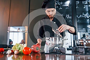 Professional young chef cook in uniform standing and preparing for the work on kitchen