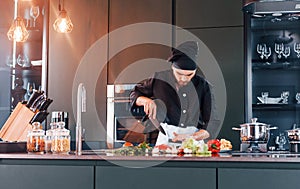 Professional young chef cook in uniform standing and preparing for the work on kitchen