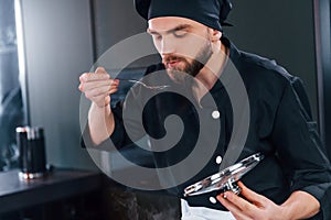 Professional young chef cook in uniform standing and preparing for the work on kitchen