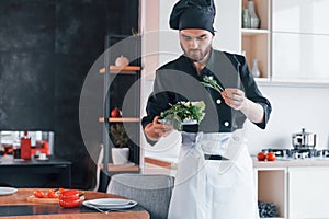 Professional young chef cook in uniform standing and preparing for the work on kitchen