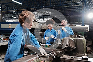 Professional young female worker with team in metalwork manufacturing factory