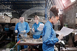 Professional young female worker with team in metalwork manufacturing factory