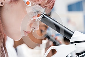 Professional young scientists working with microscopes in chemical laboratory