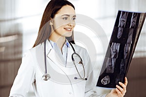 Professional young woman-doctor is looking at her patient& x27;s roentgenogram. Physician at work in a clinic& x27;s photo