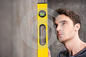Professional young worker measuring wall with level tool