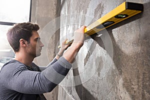 Professional young worker measuring wall with level tool