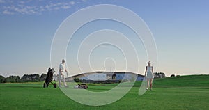 Professionals golf group play sport game on field. Business couple enjoy sunset.