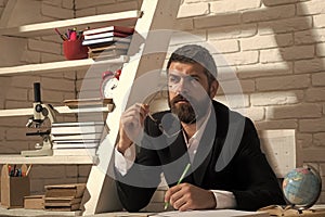 Professor with concentrated face expression sits at desk